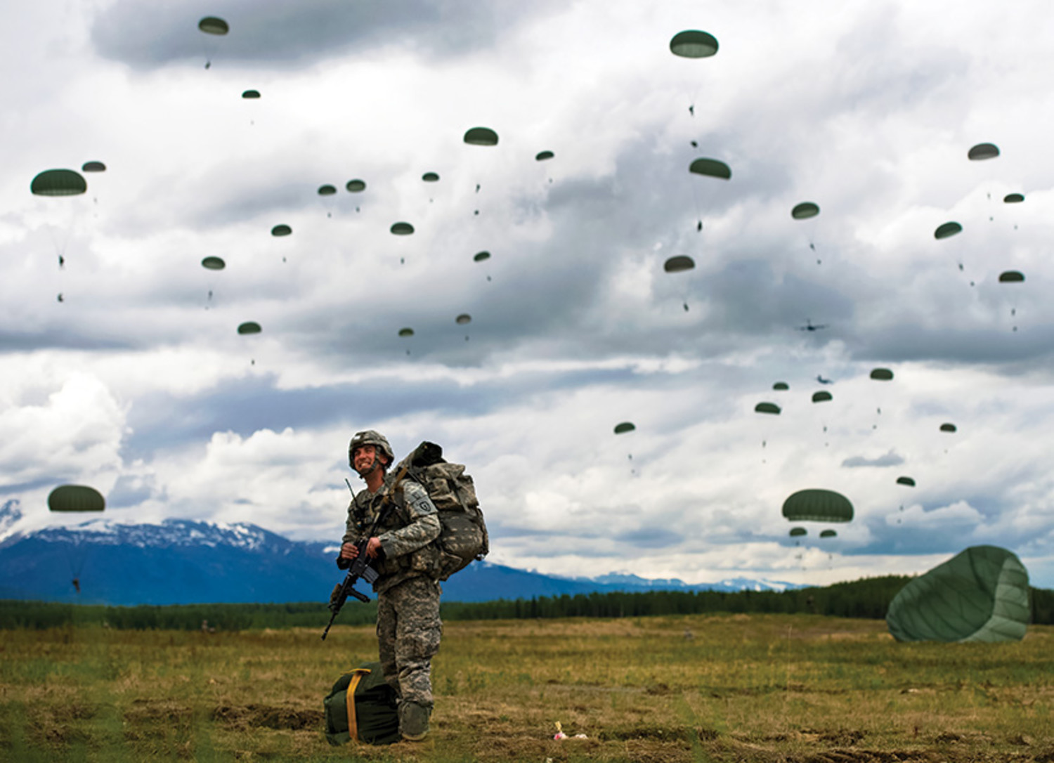 Staff Sgt. Otis Lee watches from the grounds as other Army paratroopers come down onto the Malemute Drop Zone. Soldiers from the 4th Brigade Combat Team, 25th Infantry Division (Airborne) conducted a mass tactical training exercise at the Malemute Drop Zone on Joint Base Elmendorf-Richardson on June 4, 2013. About 550 paratroopers jumped from C-17 aircraft during the exercise.