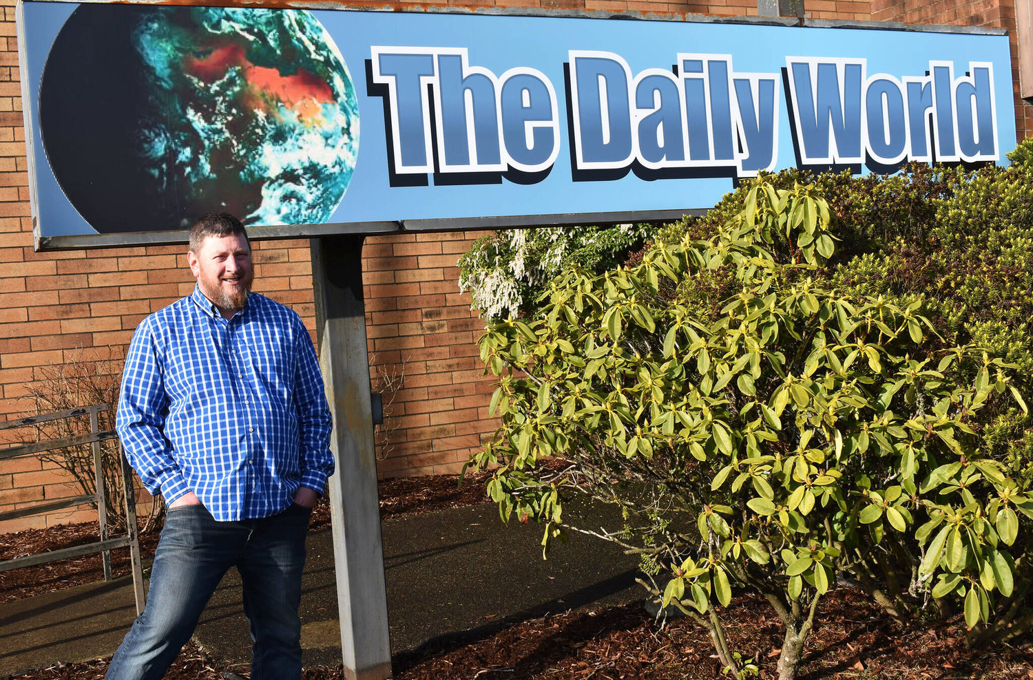 Doug Ames is the newspaper’s new interim general sales manager. Ames stands in front of The Daily World sign that he himself installed a couple months ago.